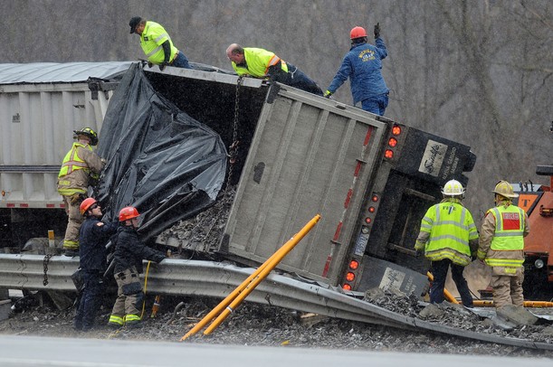 Rescue crews work to secure chains to a turned over trailer as they prepare to lift it upright using two tow trucks. The trailer flipped onto its side, spilling part of its load and pinning another vehicle against the guardrails on south U.S. 23 north of Six Mile Road in Northfield Township on Monday, March 11, 2013. Melanie Maxwell I AnnArbor.com